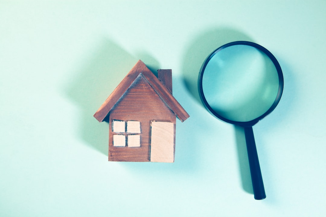 House model and magnifying glass on blue background. Property search concept.